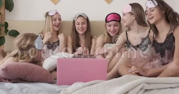 在睡衣派对上十几岁的女孩在笔记本电脑上享受媒体内容视频的预览图
