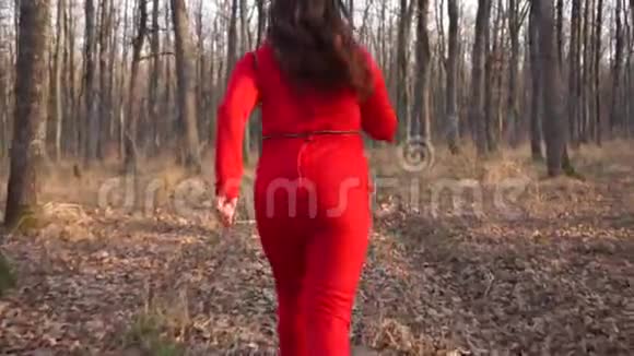 穿着红色衣服的胖姑娘穿过秋天的森林得超重慢动作视频的预览图