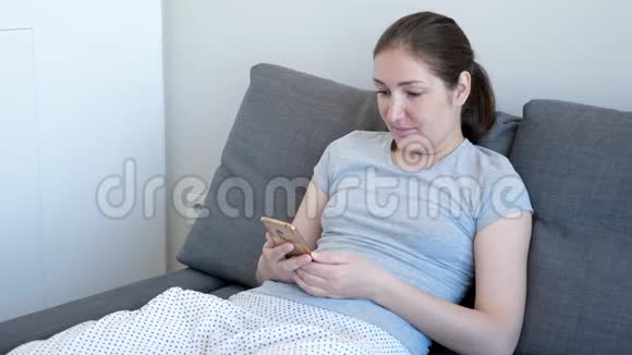 女人坐在沙发上用手机看一些有趣的东西视频的预览图