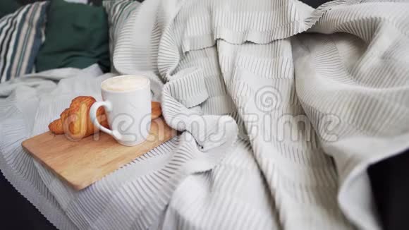 静态新鲜咖啡和一个热牛角面包在一个大沙发与枕头毛毯和格子Hygge或Lagom视频的预览图