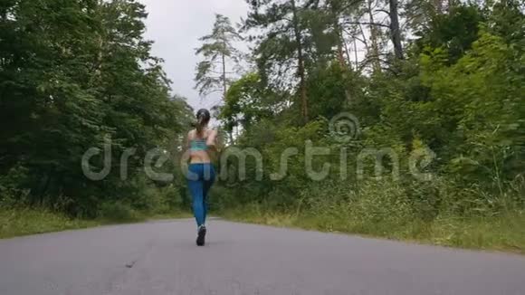 跑步的女人在森林里的路上缓慢地奔跑和跳跃户外健身用安定剂射击视频的预览图