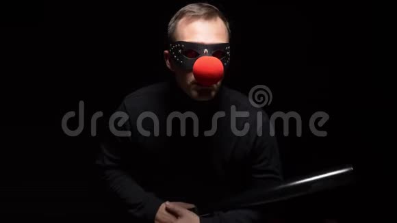 戴着红色小丑鼻子的人在黑色背景上挥舞着蝙蝠视频的预览图
