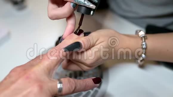 美甲师正在美甲沙龙里用暗红色指甲油涂旧女指甲视频的预览图