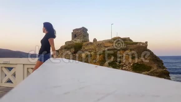 位于希腊的塞克拉兹德的安德罗斯岛上一名女子在城堡前放松视频的预览图