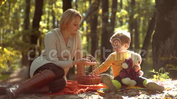 欢乐的家庭一起野餐在公园里的黄秋天一起放松微笑的母子走过来视频的预览图