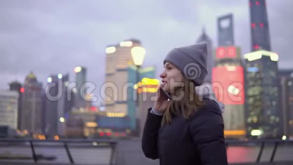 一个穿着黑色夹克和帽子的年轻女孩在打电话时悠闲地散步视频的预览图