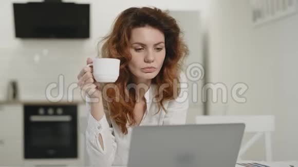 浓缩的女人在早晨的厨房喝茶年轻女士在工作视频的预览图