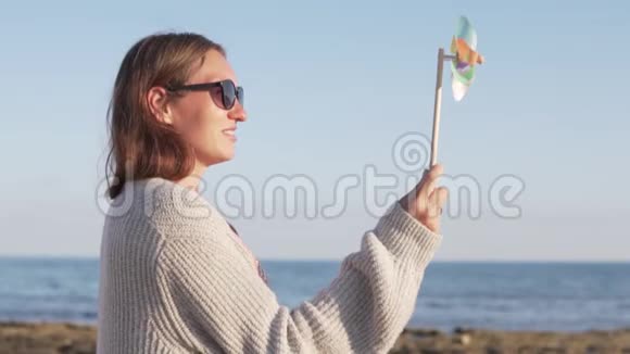 夏日假期戴太阳镜的美女玩玩具风车视频的预览图