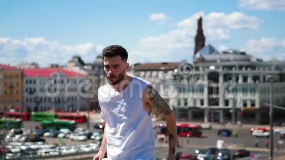 年轻迷人的男子纹身自由式舞蹈在市中心的顶端看着镜头视频的预览图