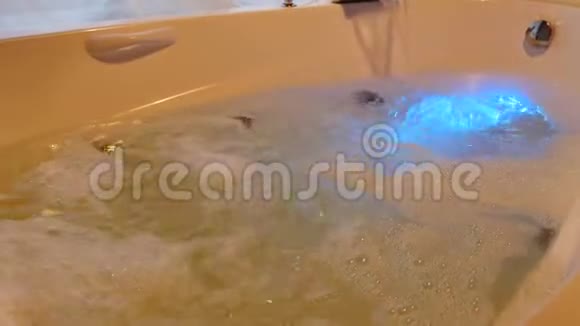用水和泡沫填充浴缸用泡沫将水流入浴缸带内助推灯的按摩浴缸快关门中弹视频的预览图