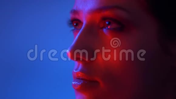 精彩时尚模特的特写镜头红色霓虹灯闪烁的眼影双手划过她的脸庞视频的预览图