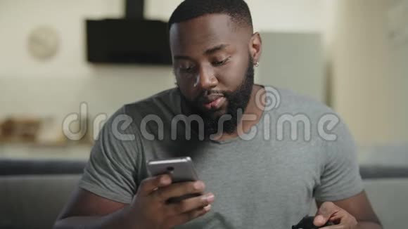 黑人在厨房拿着电话特写年轻人在智能手机上发短信视频的预览图