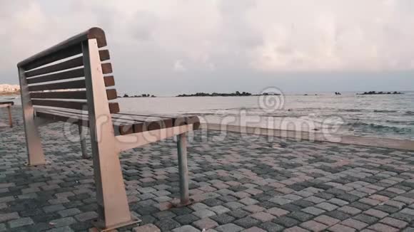 海滩上被遗弃的长凳岩石海岸附近荒凉的长凳码头木凳的侧视图暴风雨中孤独的长廊视频的预览图