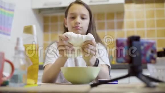 女生在厨房里拉伸和挤压自制的毛茸茸的黏液视频的预览图