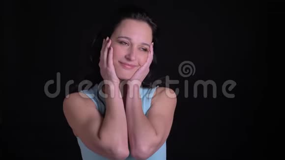 中年妇女在黑色背景上摸着脸和微笑的肖像视频的预览图