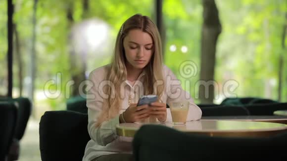 美丽的女人使用智能手机夏季咖啡馆视频的预览图