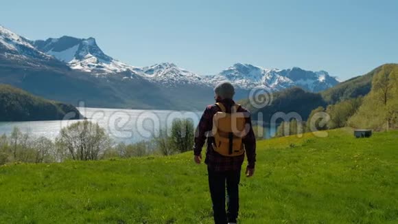 旅行者走在绿草如茵的小山上有着令人叹为观止的挪威山景视频的预览图