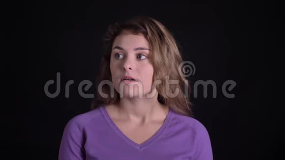 可爱的女人在镜头中积极思考和点头的肖像以显示对黑色背景的一致视频的预览图
