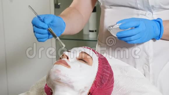 在美容中心女性美容师制作护肤抗衰老白色面膜宏观的高清高清视频的预览图