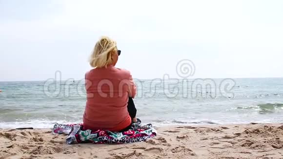 旅行和度假成年金发女人坐在大海上放松视频的预览图