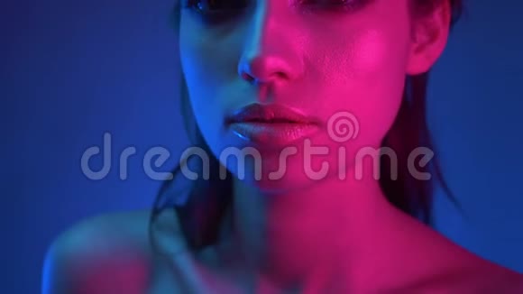 特写镜头在模特的侧面蓝色和粉红色霓虹灯注视着镜头伸出它视频的预览图