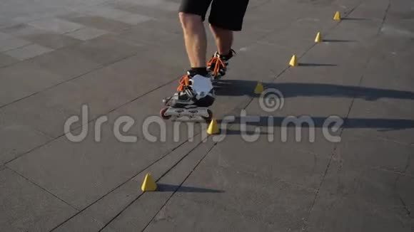在城市公园里一个年轻人在傍晚夕阳下在圆锥形的球果之间专业滑冰特写腿自由式视频的预览图