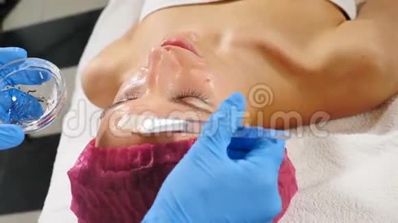 现代美容院年轻女性客户面部抗衰老手术的俯视图蓝色美容师视频的预览图