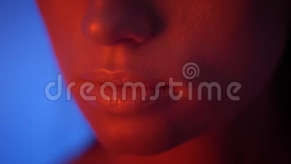 红色霓虹灯的未来时尚模特的特写镜头她的手在蓝色背景上穿过她的脸视频的预览图