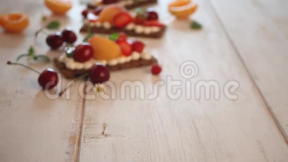 女人手在白色的木制背景上放着奶油奶酪水果和浆果的脆健身保健面包视频的预览图
