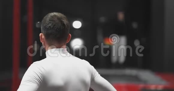 男子体操运动员在蹦床中心后面观看表演的技巧对手视频的预览图