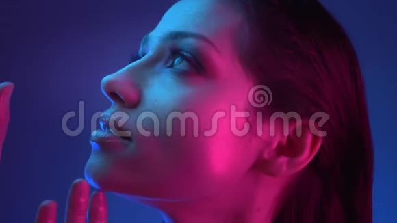 蓝粉色霓虹灯模特形象特写镜头带着娱乐的眼光向上看伸手视频的预览图