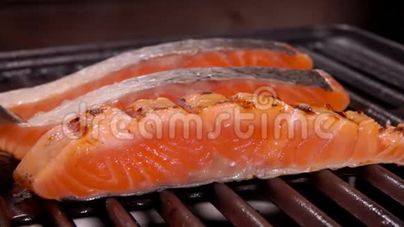 厨师在烤架上用金属钳翻转一条生鲑鱼视频的预览图