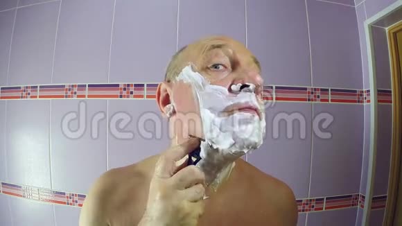 浴室里的一个人用剃刀剃掉鬓角上的胡茬视频的预览图