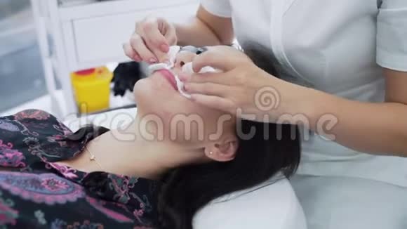 面部护理前美容师用湿棉布垫清洁女性皮肤动作缓慢视频的预览图