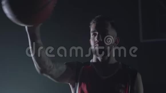 特写肖像英俊自信的男人穿着红色制服在黑暗中伸出手拿着一个球专业人员视频的预览图