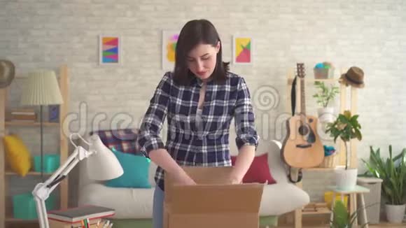 年轻女子高兴地打开一个装有包裹的盒子视频的预览图