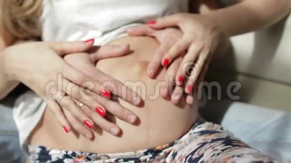 爸爸妈妈把手放在怀孕的肚子上怀孕夫妇抚摸怀孕的肚子视频的预览图
