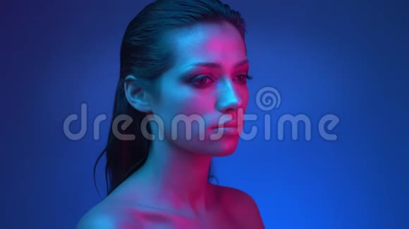 未来派模特在蓝粉色的霓虹灯中她的眼睛从左向右移动视频的预览图