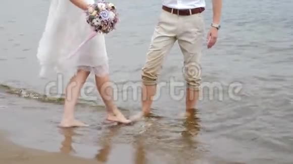 快关门一对光着脚的年轻夫妇沿着海滨散步男人和女人沿着沙岸走没有穿鞋爱情视频的预览图