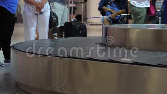 行李传送带上的手提箱在机场的行李认领等待行李的人视频的预览图