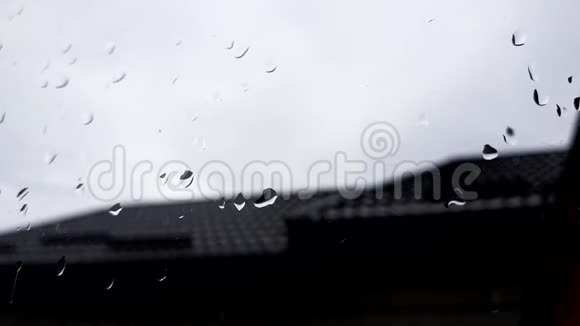 窗外有雨滴背景中模糊的多云天空和屋顶视频的预览图