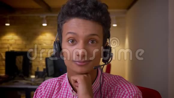 印度年轻商人戴着耳机在办公室里开心地看着摄像机的特写镜头视频的预览图