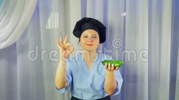 女人穿着围裙做饭微笑着手里拿着新鲜的黄瓜露出她的手好吗视频的预览图
