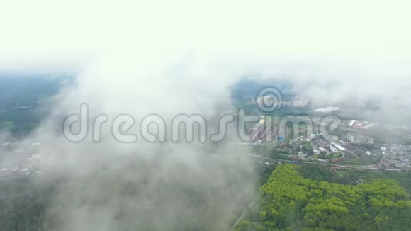 云覆盖了无人机摄像机的视野覆盖了郊区工业区夏天飞越森林视频的预览图