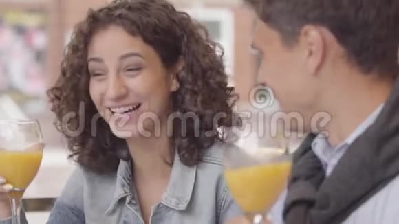 一对幸福夫妇坐在户外咖啡馆里喝橙汁时谈笑风生的肖像年轻人视频的预览图