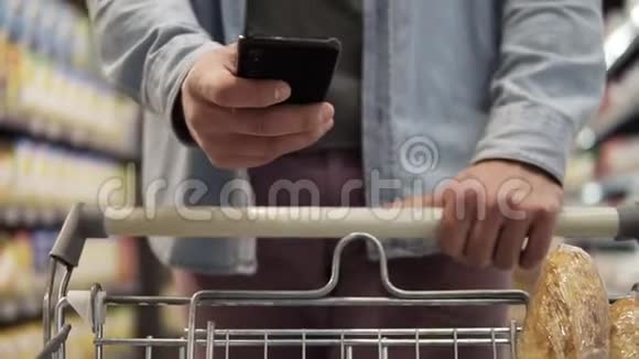一个年轻人在背景模糊的情况下推着手推车在杂货店里购物视频的预览图