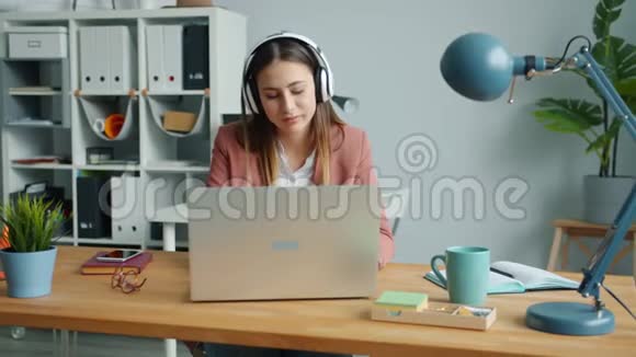创意办公室工作人员用耳机听音乐用手提电脑打字视频的预览图