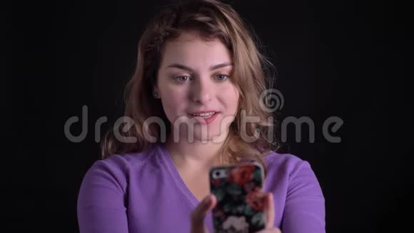 黑色背景下快乐的金发女人在智能手机上视频通话的肖像视频的预览图