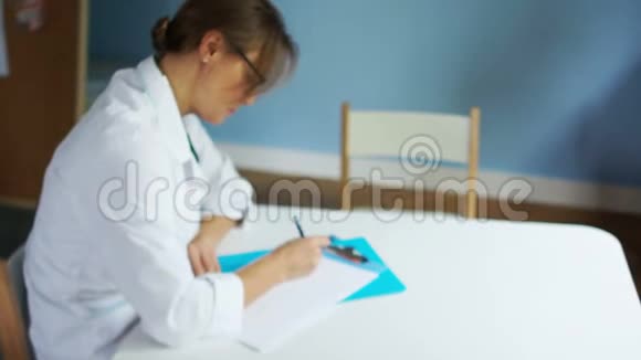 成熟严肃的女医生坐在办公室的一张桌子旁为病人开出一张处方保健和保健视频的预览图
