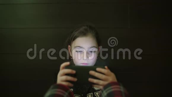 儿童少年女孩的夜间镜头女孩的脸浏览平板电脑或智能手机上面有光反射视频的预览图